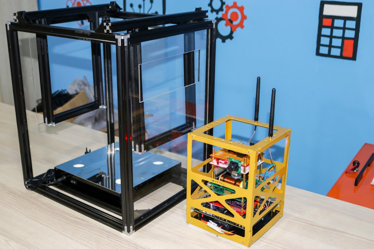 3D printer with acrylic enclosure and electronic device with wireless communication capability in IVY STEM International School's technology lab.